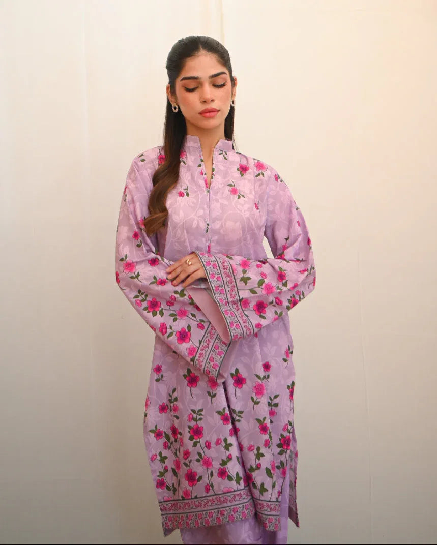 Woman wearing a pink floral printed dress which includes a shirt and shalwar.