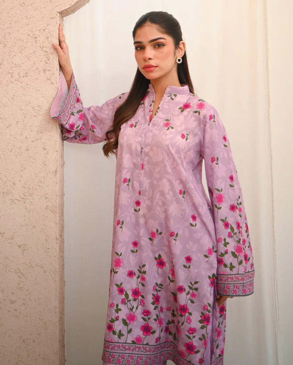 Woman wearing a pink floral printed dress which includes a shirt and shalwar.