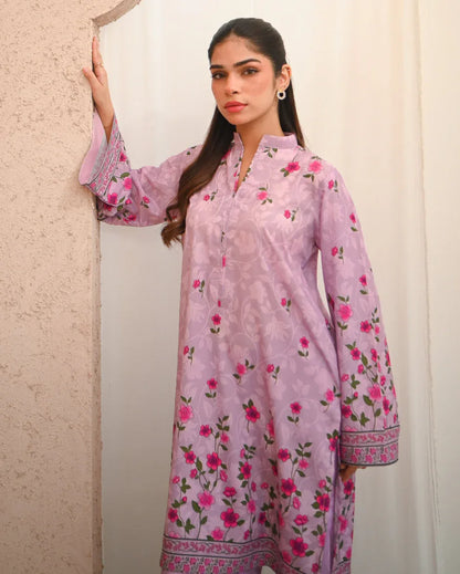 Woman wearing a pink floral printed dress which includes a shirt and shalwar.