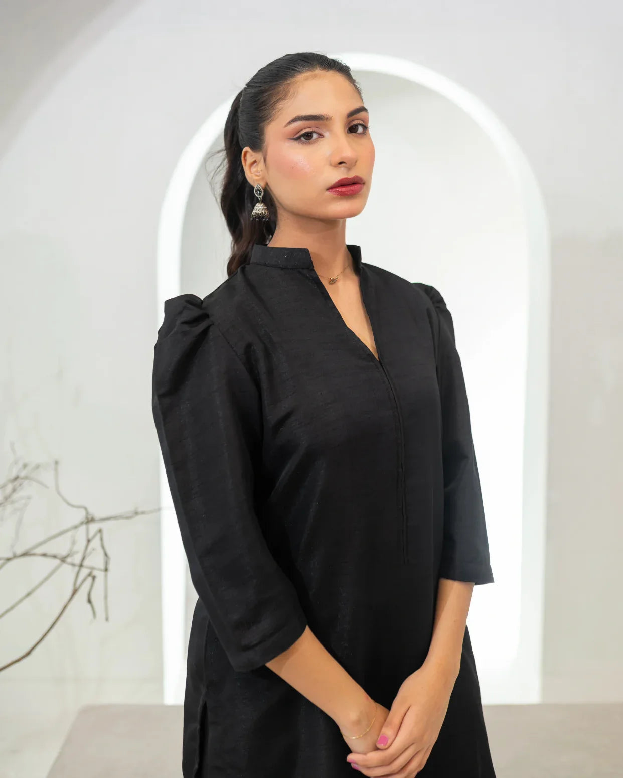 Woman wearing a black dress with puffed sleeves against a white background