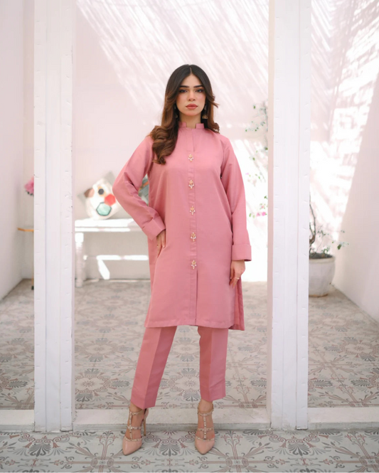 A woman wearing a pink two-piece indian rawsilk dress consisting of a shirt and trousers.
