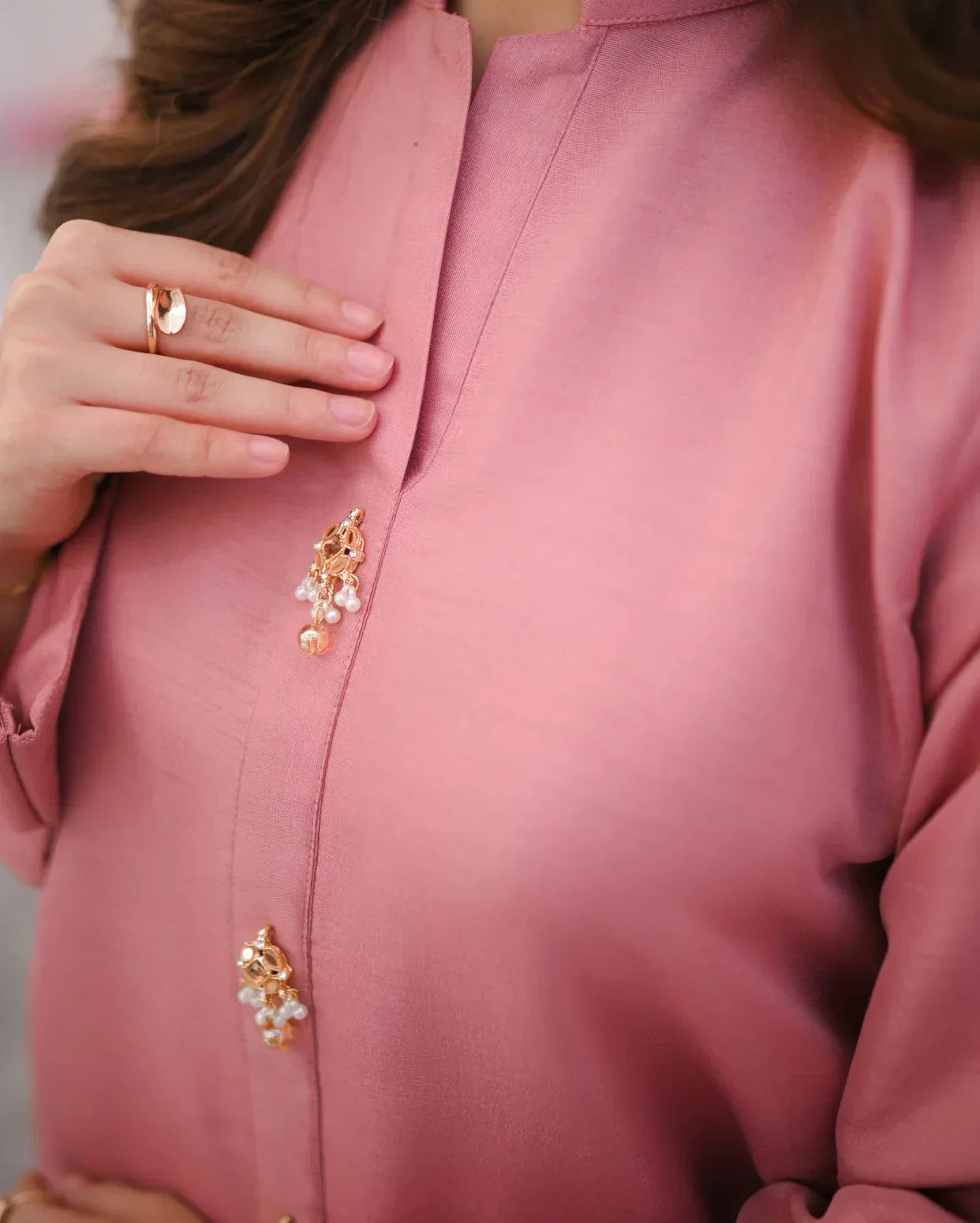 Close up of a women wearing a pink dress and highlighting the neck line.