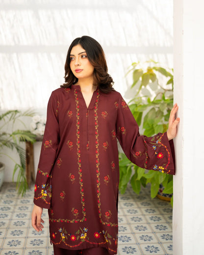 Woman wearing a maroon dress standing indoors with plants in the background