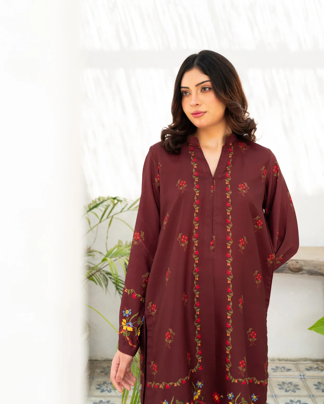 Woman wearing a maroon printed dress against a white background