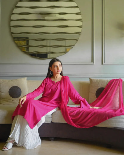 Women wearing a three piece pink color dress which includes a shirt with embroidery on sleeves, dhaka lehenga and a chiffon dupatta.