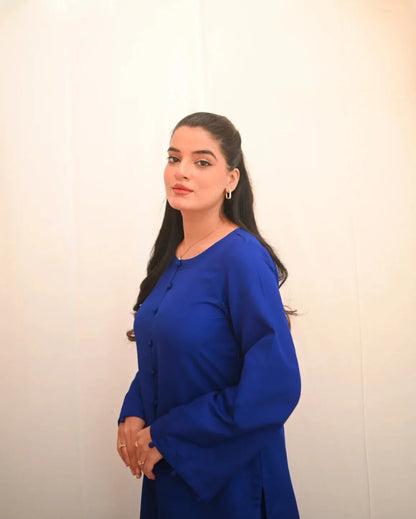 A woman standing and posing in a blue rawsilk shirt.